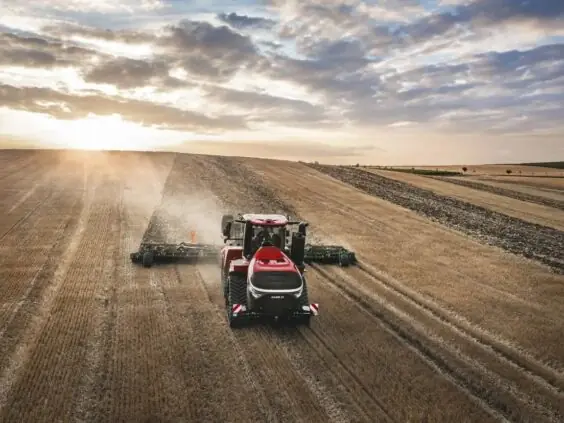 En rød Steiger 785 Quadtrac traktor i arbeid på en åker ved solnedgang.