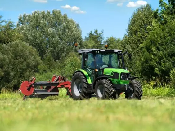 En grønn Deutz-Fahr 5D Keyline traktor som arbeider på en mark med landbruksutstyr.