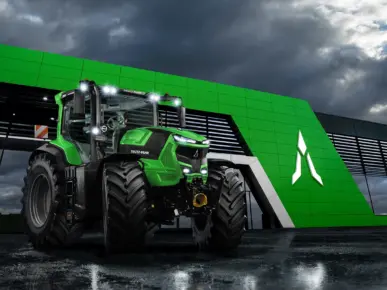Grønn Deutz-Fahr NEW Series 8 traktor foran en moderne bygning under en dramatisk himmel.