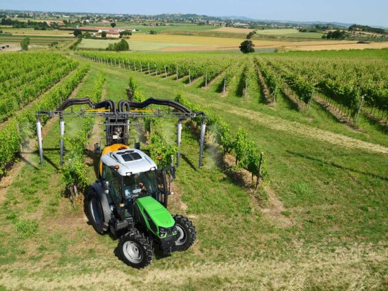 En grønn Deutz-Fahr Series 5D traktor som sprøyter vinranker i en stor vingård.