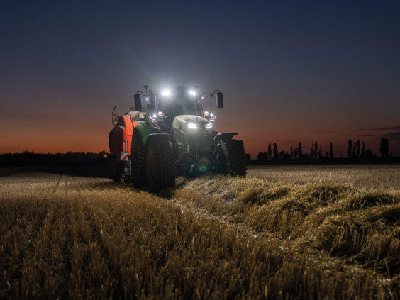 Grønn Deutz-Fahr Series 6 traktor i arbeid på kveldstid med kraftige arbeidslys tent.