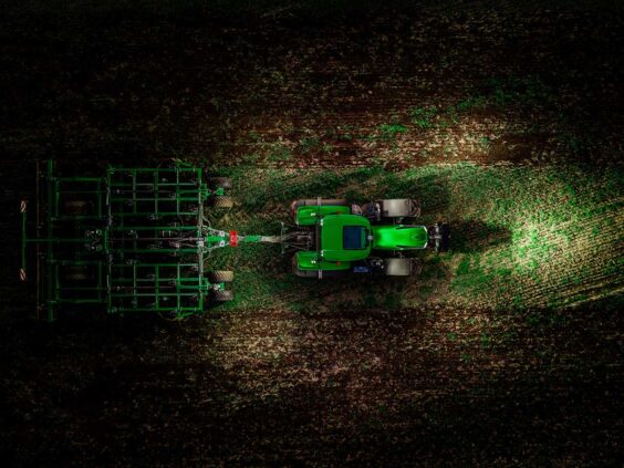 Grønn Deutz-Fahr Series 8 traktor i arbeid på åkeren, sett fra fugleperspektiv.