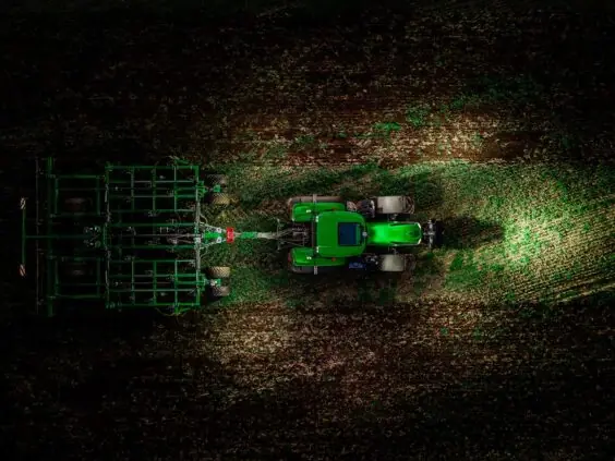 Grønn Deutz-Fahr Series 8 traktor i arbeid på åkeren, sett fra fugleperspektiv.