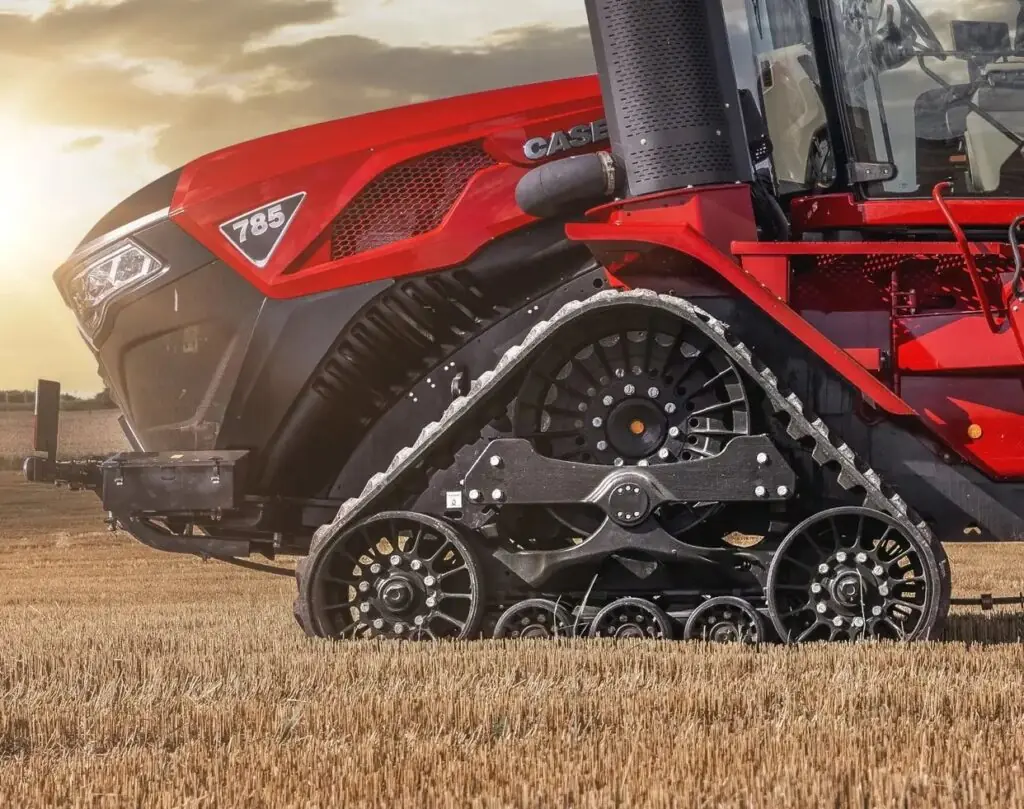 Rød Case IH Steiger 785 Quadtrac traktor med belter på en åker i solnedgang.