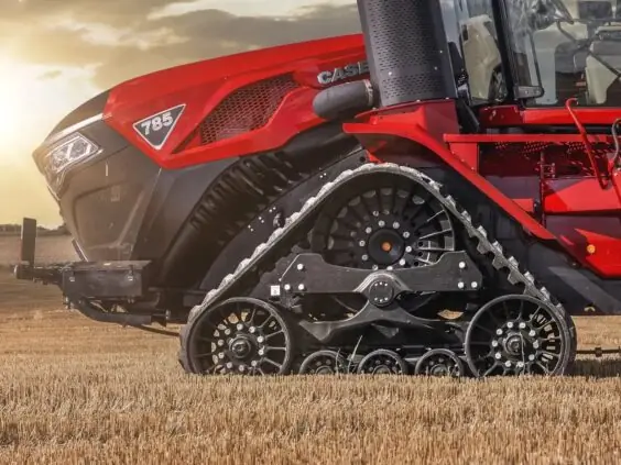 Rød Case IH Steiger 785 Quadtrac traktor med belter på en åker i solnedgang.