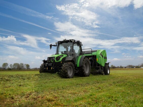 En grønn Deutz-Fahr Series 5D TTV traktor som arbeider på en gressmark under blå himmel.