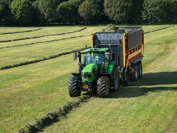 En Deutz-Fahr Series 6 traktor i arbeid på en gresskledd åker med tilhenger.
