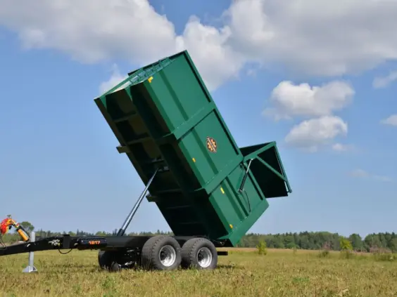 Grønn Palmse PT1317SB dumperhenger som tipper bakover på en grønn eng.