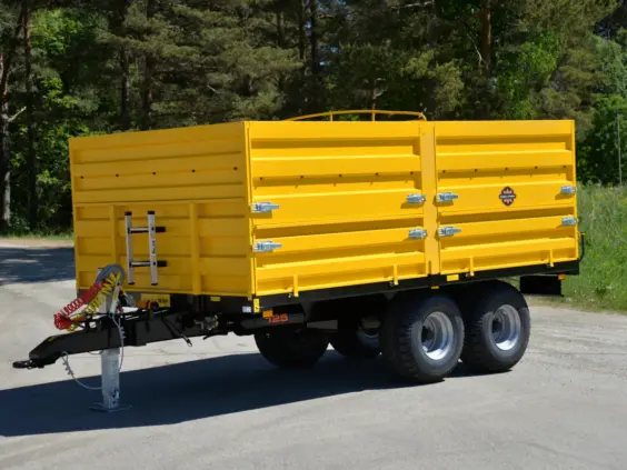 Gul Palmse Trailer PT125 kornhenger parkert utendørs med grønne trær i bakgrunnen.