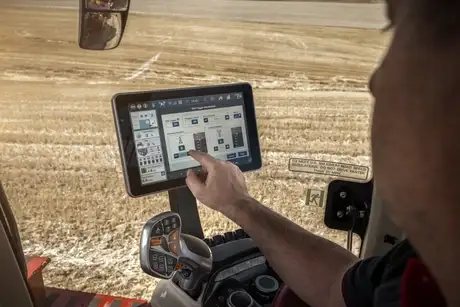 En person betjener den digitale berøringsskjermen inne i en Steiger 785 Quadtrac traktor.