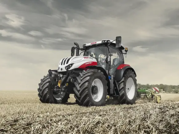 Steyr Profi CVT traktor i arbeid på en stubbeåker under en overskyet himmel.