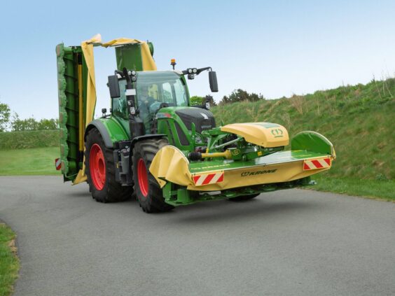 Grønn traktor med Krone EasyCut F 280 – F 320 frontslåmaskin på en asfaltvei.