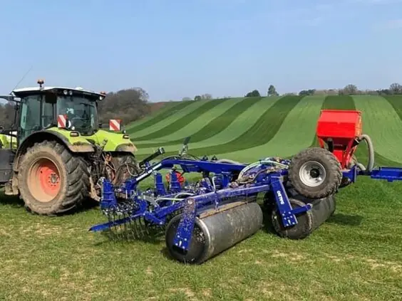 En traktor på en grønn åker med en DALBO Maxiroll Greenline 3-delt trommel.