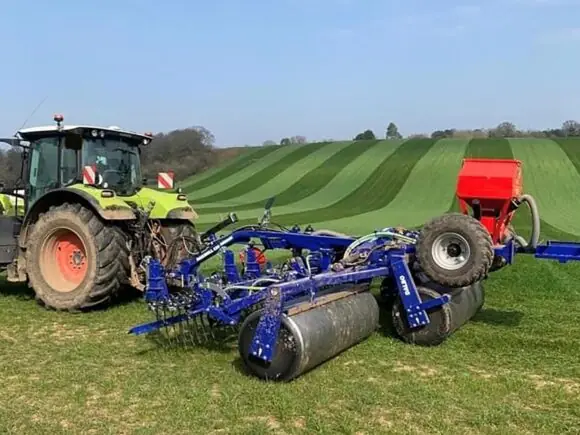 En traktor på en grønn åker med en DALBO Maxiroll Greenline 3-delt trommel.