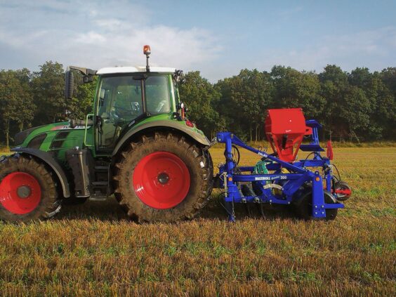 En traktor med en DALBO Maxiroll Greenline Lift, løftebåren grastrommel på en åker.
