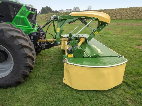 Grønn traktor med Krone EasyCut F 280 – F 320 frontslåmaskin på en gresslette.
