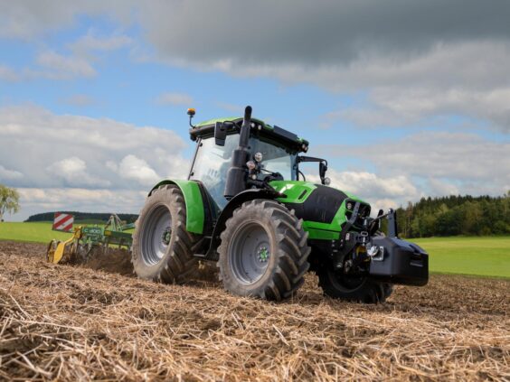 Grønn Deutz-Fahr Series 5 traktor i arbeid på en åker under en blå himmel.