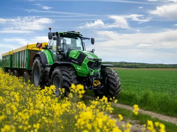 En grønn Deutz-Fahr Series 7 traktor som kjører forbi en gul rapsåker.