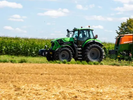 Grønn Deutz-Fahr Series 8 traktor i arbeid på en åker med en oransje såmaskin.
