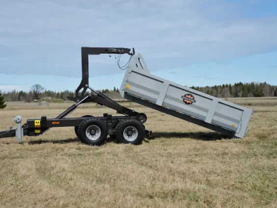 Palmse Trailer ML414 krokhenger med grå container på et jorde under en blå himmel.