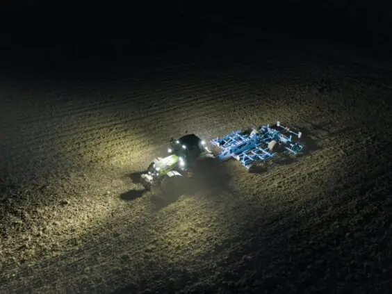 Luftfoto av en Deutz-Fahr Series 7 traktor som arbeider på en åker om natten.