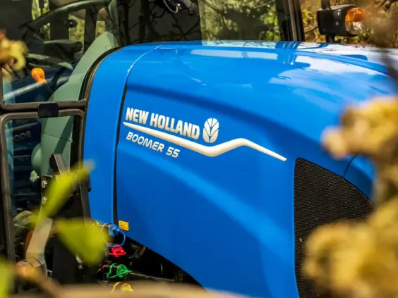 Blå New Holland Boomer 55 traktor med nærbilde av panseret og merkevarelogo.