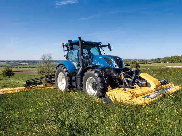 New Holland T6 med beitepusser på eng i kupert landskap