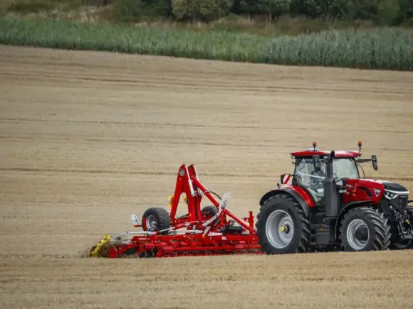 En rød Optum 360-440 traktor i arbeid på en åker etter innhøsting.
