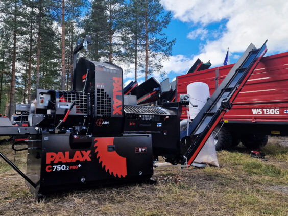Svart og rød Palax C750.2 vedmaskin i arbeid utendørs ved skogen.