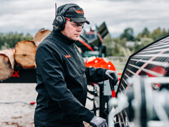 En mann som betjener en Palax D410 vedmaskin utendørs med verneutstyr.