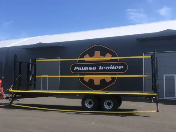 Palmse PT3750PS plattformhenger med gule detaljer parkert foran en stor Palmse Trailer-bygning.