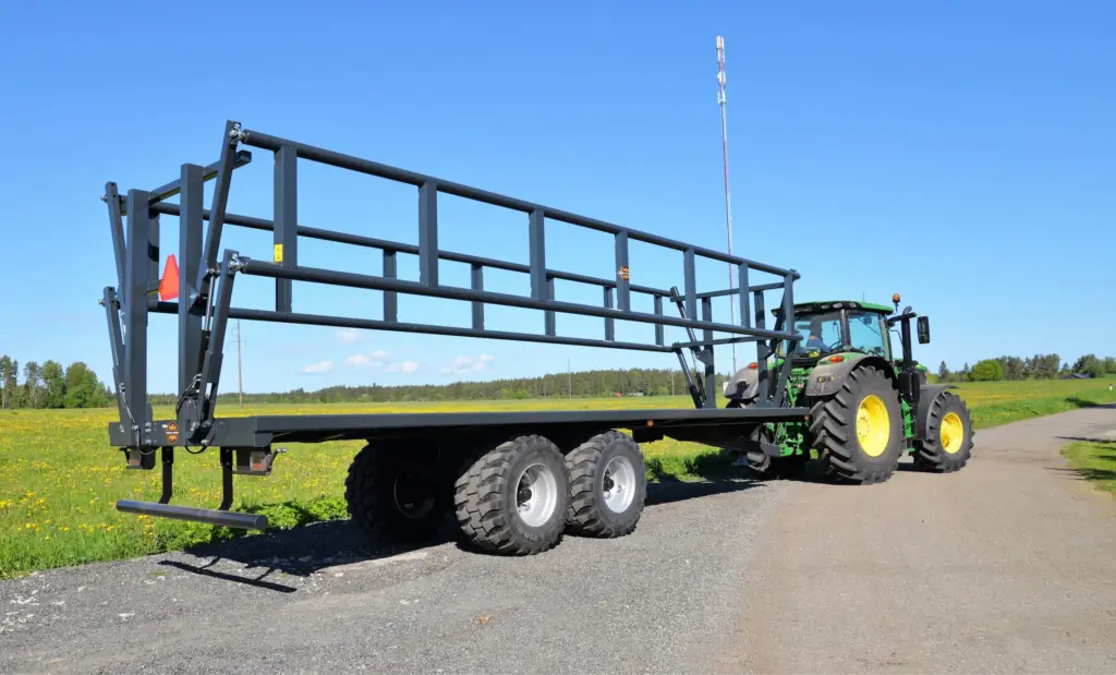En Palmse PT3925-19T ballhenger koblet til en grønn traktor på en grusvei.