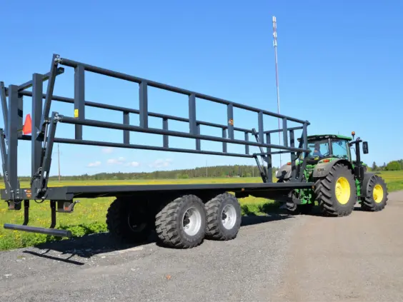 En Palmse PT3925-19T ballhenger koblet til en grønn traktor på en grusvei.