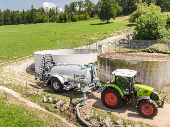 En Claas-traktor med Pichon fyllesystemer for vakumvogner ved en gjødselkum på et grønt jorde.