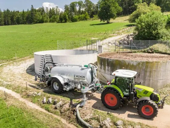 En Claas-traktor med Pichon fyllesystemer for vakumvogner ved en gjødselkum på et grønt jorde.
