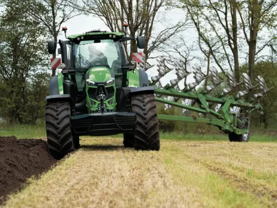 Grønn Deutz-Fahr Series 7 traktor som pløyer en åker med en stor vendeplog.