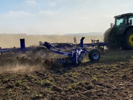 En traktor som trekker en DALBO Powerchain i arbeid på jordet.