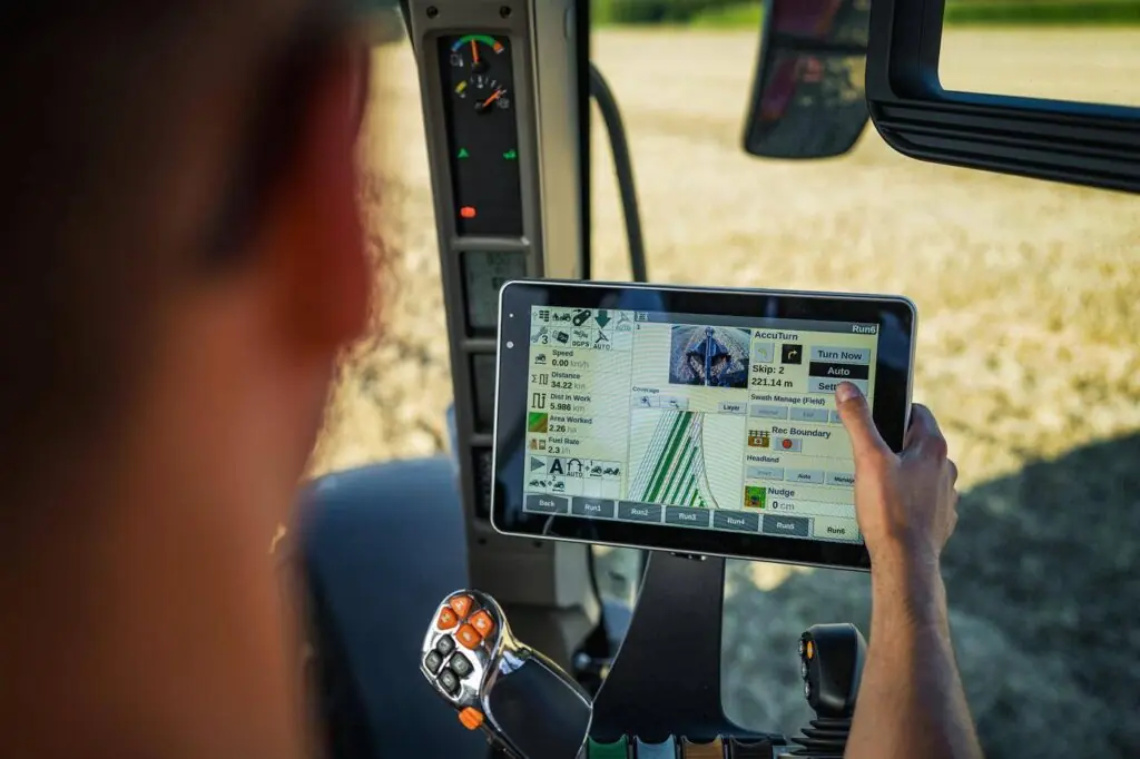 En fører betjener kontrollskjermen i en traktor fra Vestrum-serien under arbeid på feltet.
