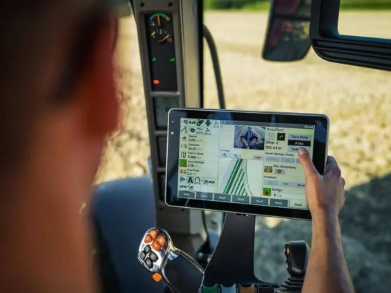 En fører betjener kontrollskjermen i en traktor fra Vestrum-serien under arbeid på feltet.