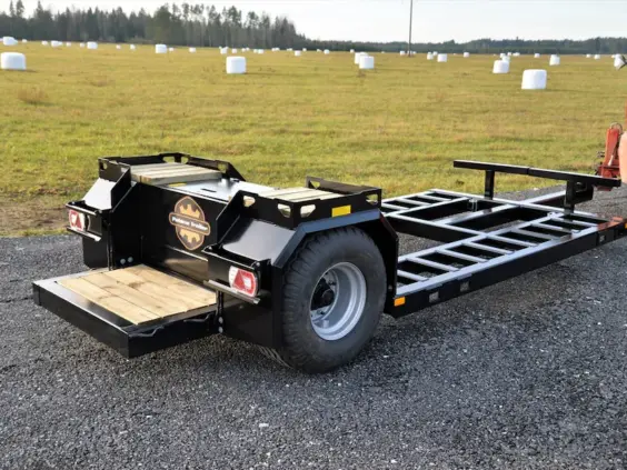 En robust Palmse PT5350 maskinhenger står parkert på en grusvei ved et jorde.