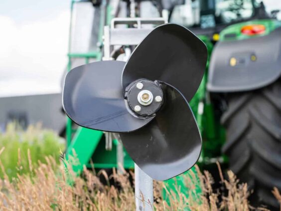 Nærbilde av en svart propell på en SAMSON RV-150 gjødselmikser foran en grønn traktor.