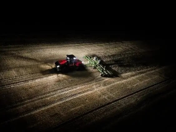 En rød Steiger 785 Quadtrac traktor arbeider på en åker om natten med kraftig belysning.