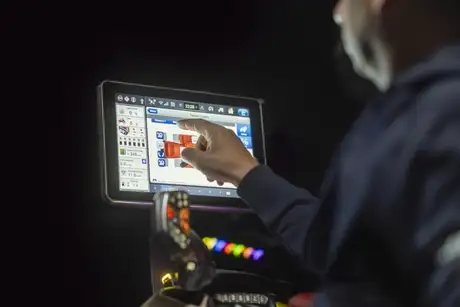 En person bruker den digitale berøringsskjermen i førerhuset på en Steiger 785 Quadtrac traktor.