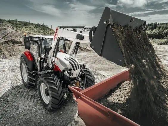 Steyr Expert tømmer grus fra frontlasteren i et grustak