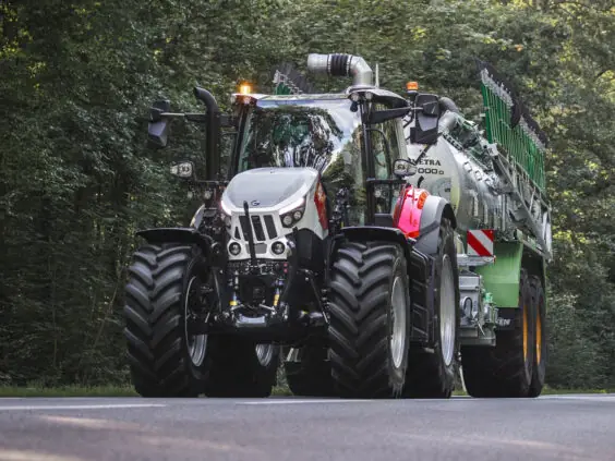 Steyr Impuls med gjødselvogn sett forfra på en skogkledd veistrekning