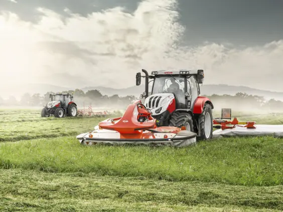 Steyr Profi 6145 med front- og bakmontert slåmaskin på eng