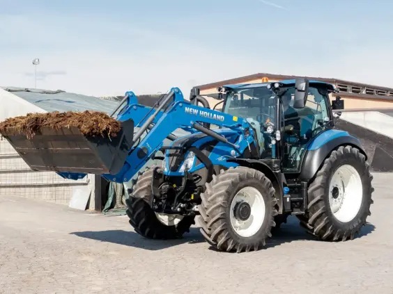 Blå New Holland traktor T5 Dynamic Command og Auto Command med frontlaster i arbeid.