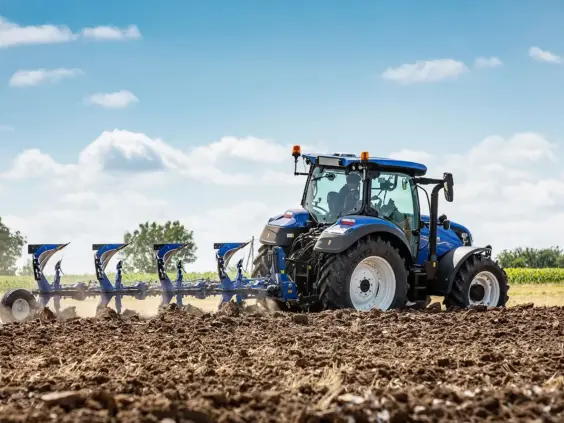 Blå traktor T5 Dynamic Command og Auto Command som pløyer en åker under blå himmel.