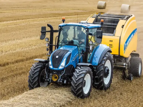 Blå New Holland T5 Electro Command traktor som presser halm i en åker.