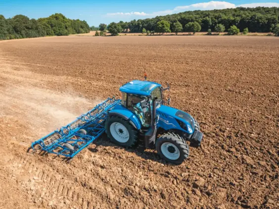 En New Holland T5 Electro Command traktor som bearbeider jorden på en stor åker.